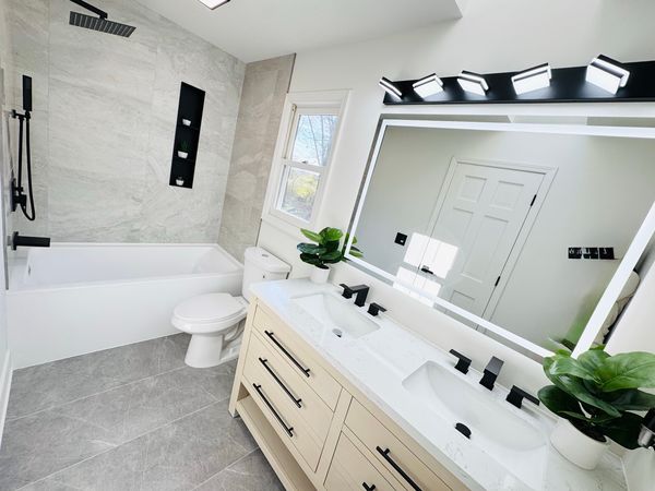 Bathroom with a white double vanity, a large lit mirror and gray tile