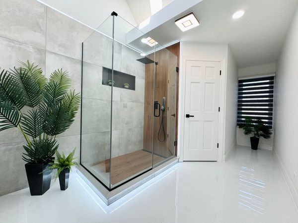 Bathroom after the remodel, with a large walk-in glass shower and a glossy white floor
