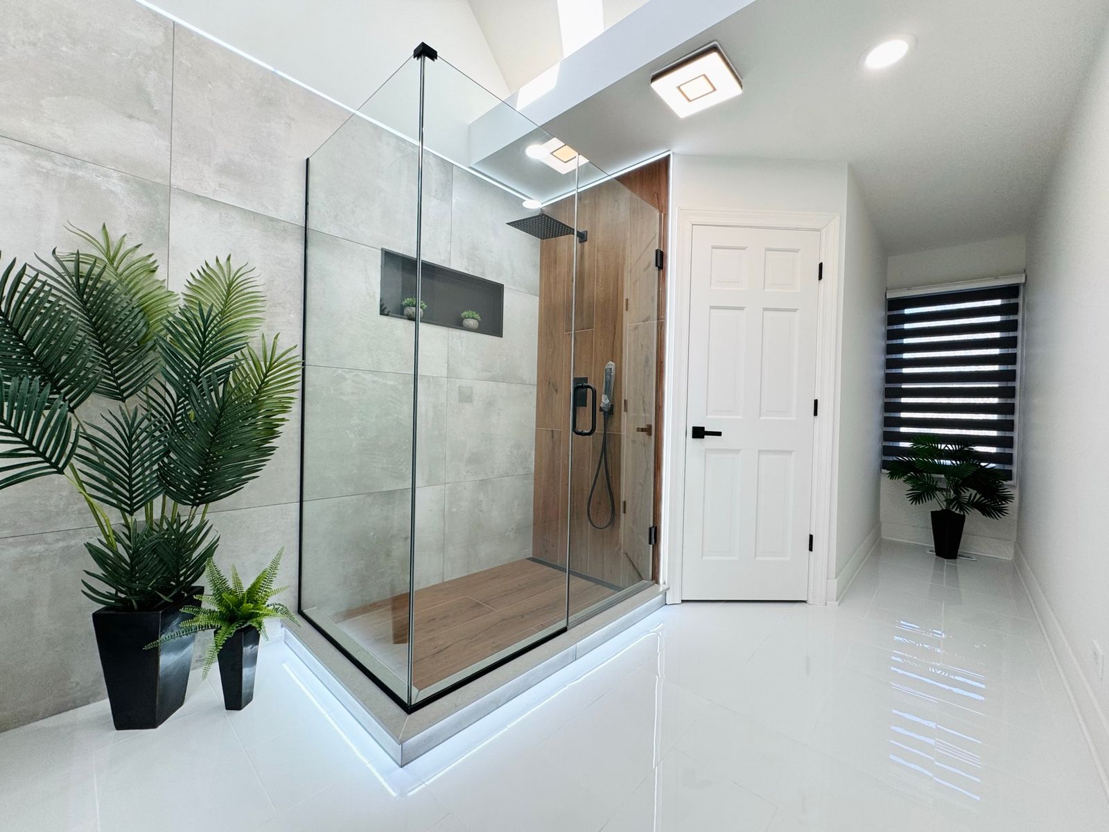 Bathroom after the remodel, with a large walk-in glass shower and a glossy white floor