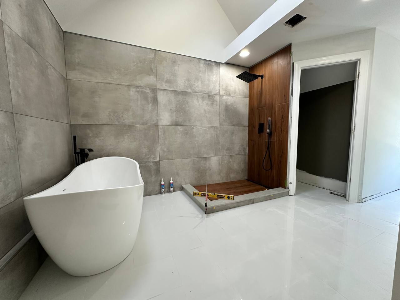 Bathroom during the work, with the freestanding tub in place and the shower floor being leveled