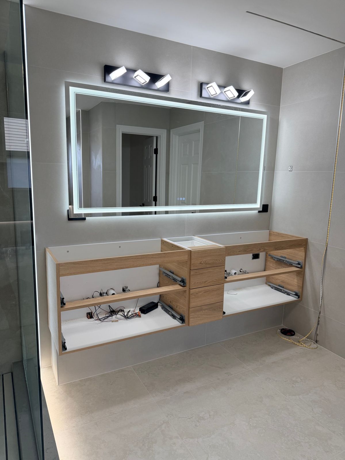 Floating wood vanity in place, with its sinks and fixtures not yet installed