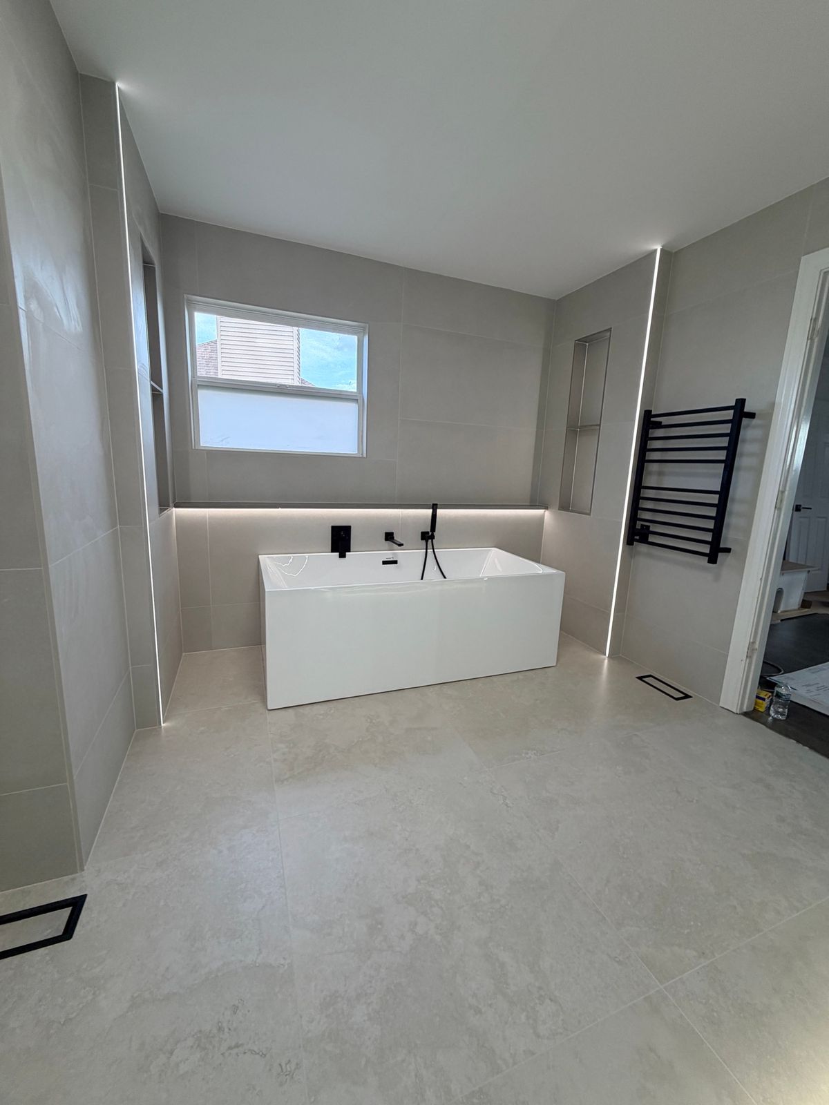 Freestanding tub in an alcove with a warm gray tile wall
