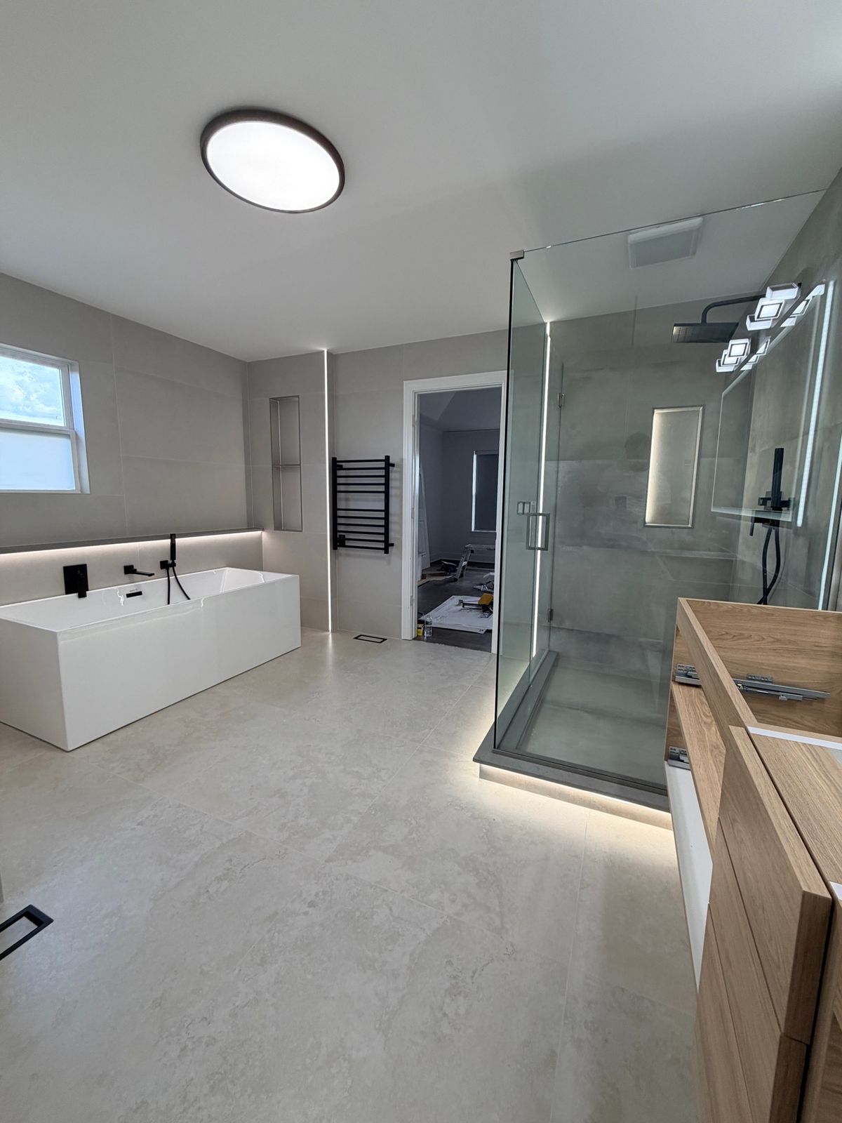 Bathroom with a freestanding tub, a glass shower and a round ceiling light