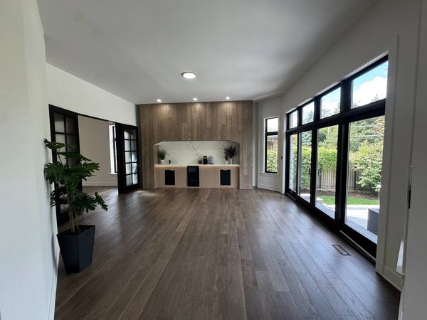 Open living area with a wood-look feature wall, a niche and large black-framed windows and doors