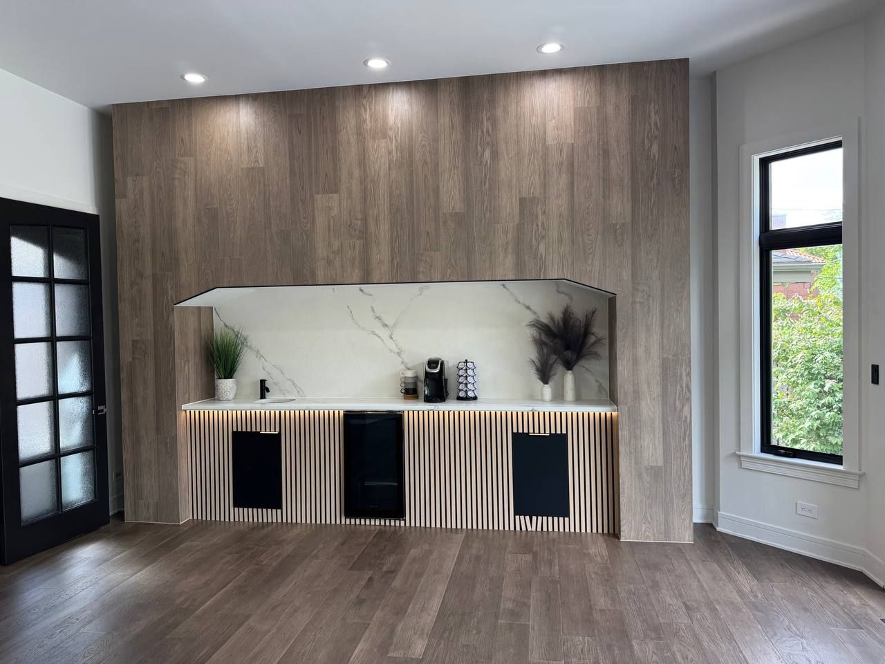 Coffee-bar niche in a wood-look wall, with a slat-panel base cabinet and a marble-look back panel