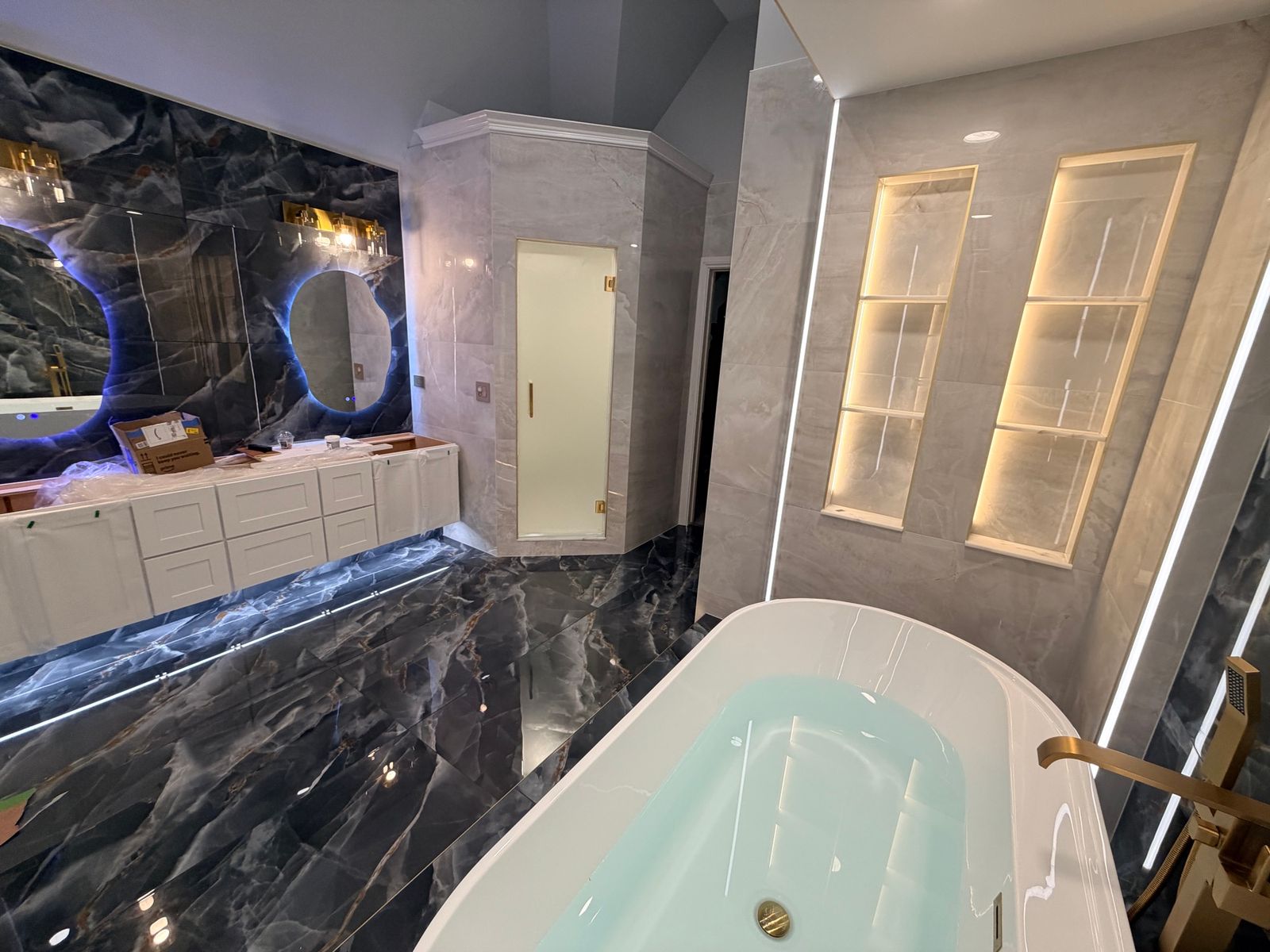 Primary bathroom with dark onyx-look tile, a freestanding tub and lit wall niches