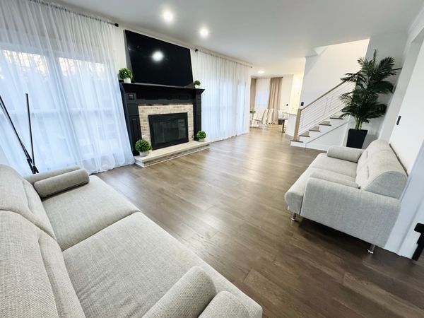 Living room after, with a new plank floor, a black fireplace surround and white sofas