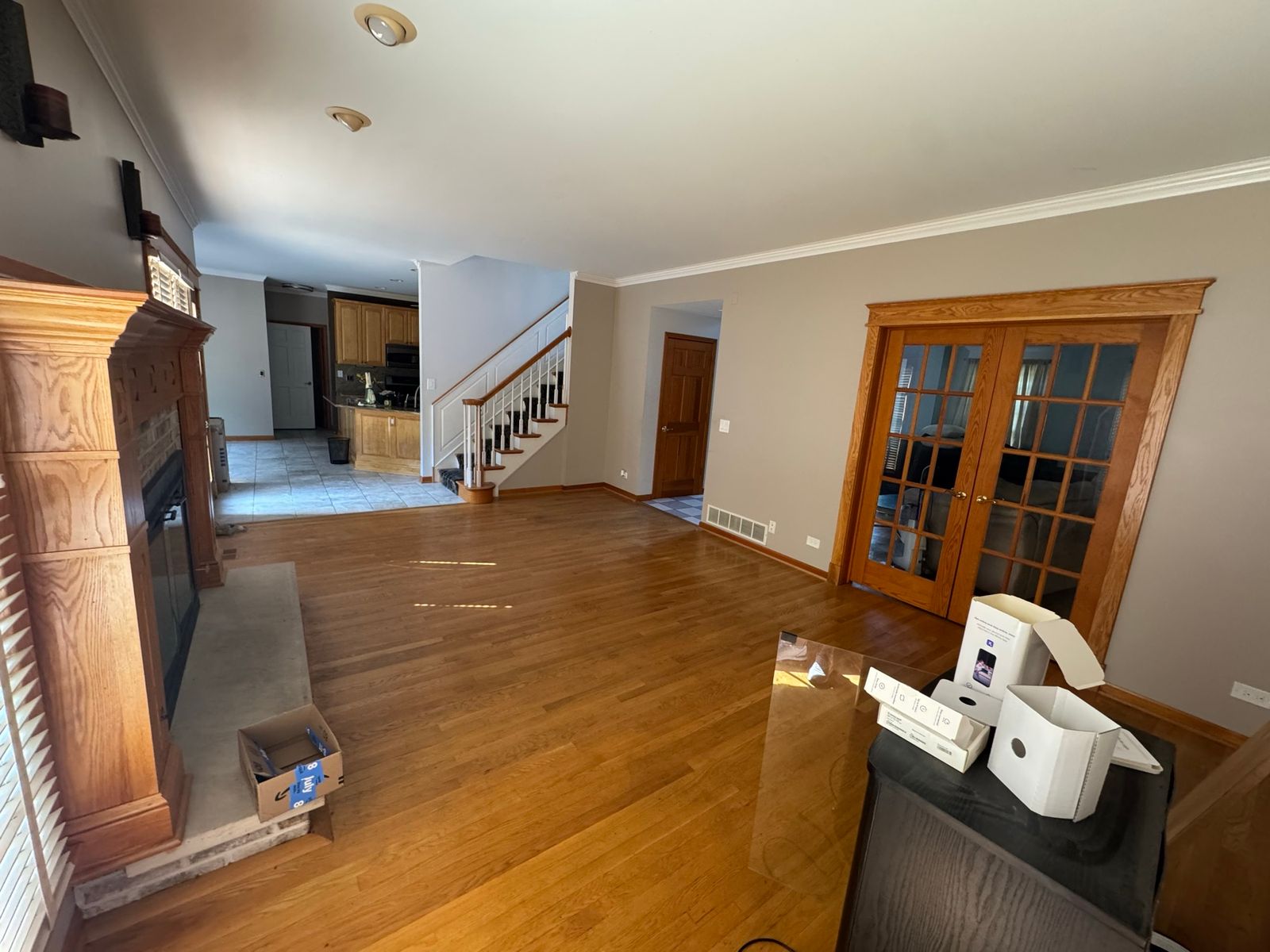 The living room before, seen toward the kitchen, with oak floors and a wood-mantel fireplace