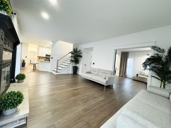 The living room after, seen toward the kitchen, with a plank floor and a black fireplace surround
