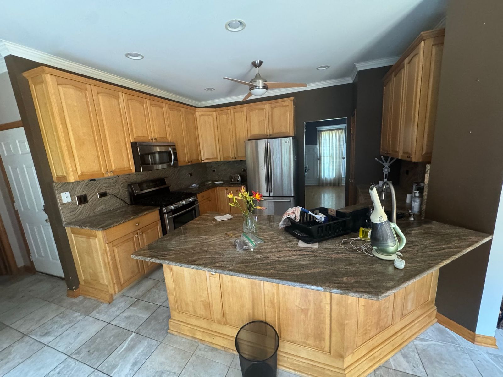 Kitchen before the remodel, with oak cabinets, dark counters and gray floor tile