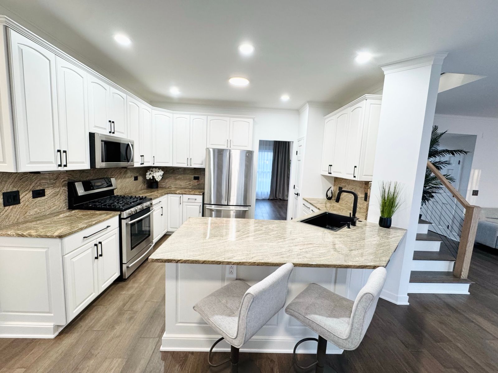 Kitchen after the remodel, with white shaker cabinets, light countertops and a plank floor