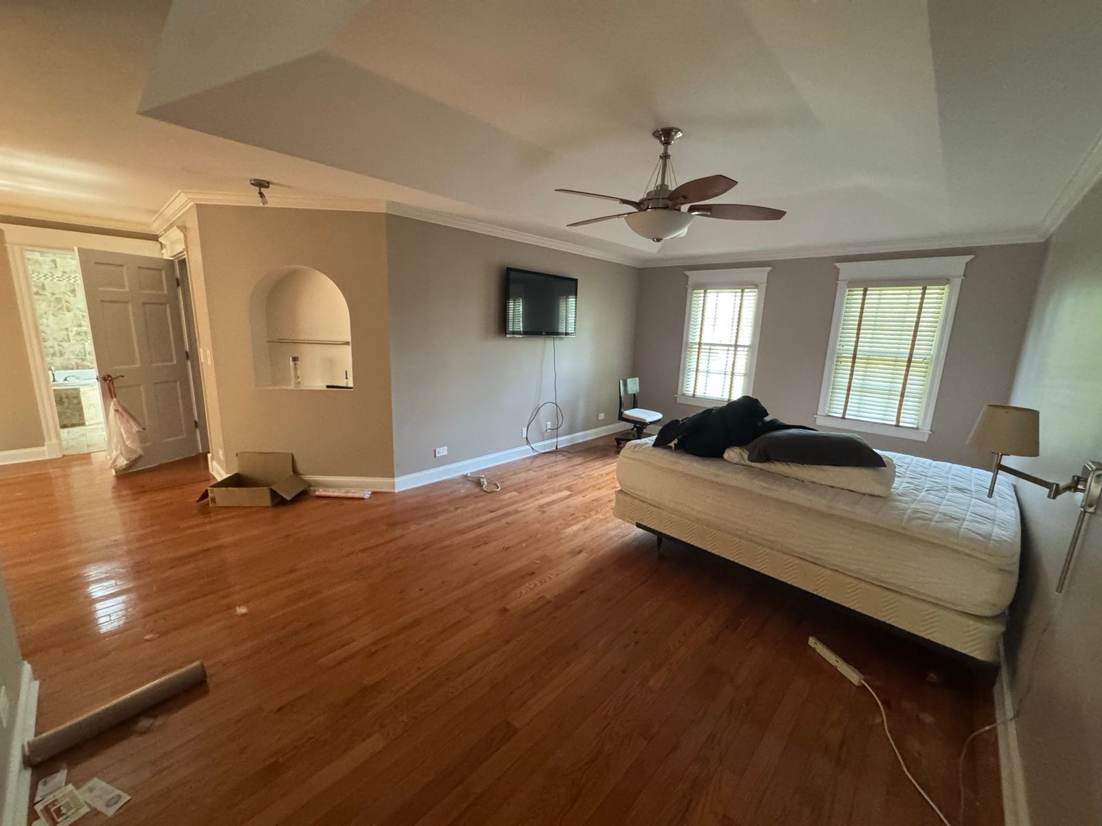 Bedroom before, with orange hardwood floors and taupe walls